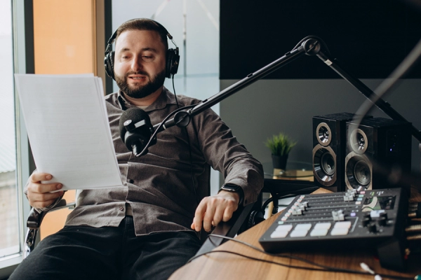 Animateur radio en studio lisant son script au micro à Caen